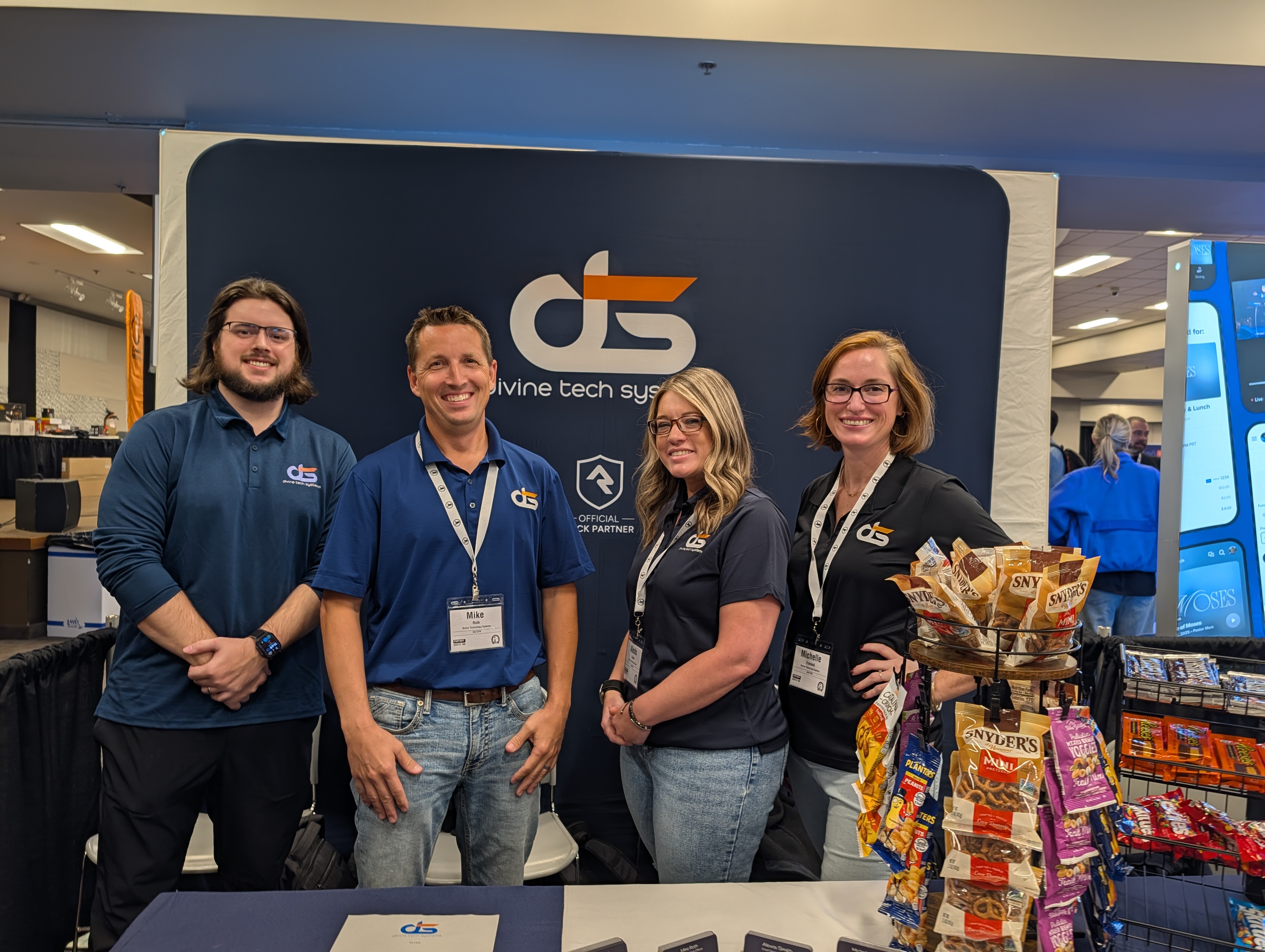 Four members of the Divine Tech Systems team smiling in front of the DTS booth at CITN